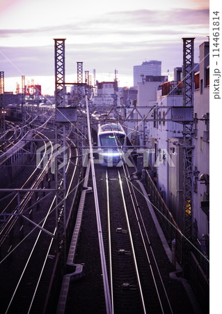 夕暮れの線路を走る電車 114461814