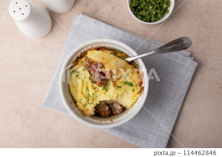Shepherd's pie in a portioned white baking dish. Homemade traditional casserole (gratin) with minced meat and mashed potatoes. Selective focus, close-up. 114462846
