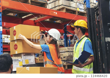 Warehouse management team use bar code scaner scan goods shelf writing checklist on clipboard. Asian men women worker check stock inventory. Teamwork logistics staff counting products store inventory 114466420