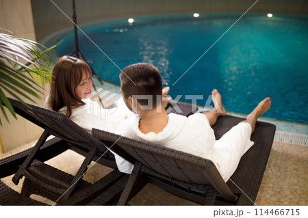 two loving couples sitting in bathrobes by the swimming pool two loving couples sitting in bathrobes by the swimming pool 114466715