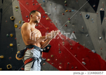 Climber coating his hands in powder chalk magnesium to climb indoor, close-up 114466857