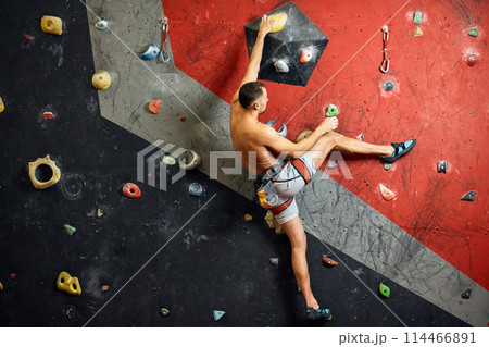 Male professional climber at indoor workout at bouldering centre. Male professional climber at indoor workout at bouldering centre. 114466891