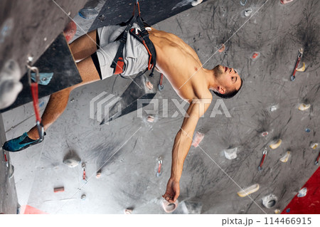 Male professional climber at indoor workout at bouldering centre. Male professional climber at indoor workout at bouldering centre. 114466915