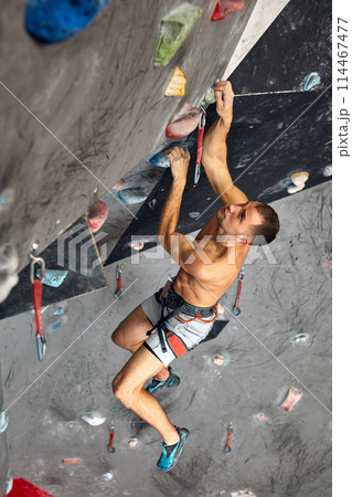 Male professional climber at indoor workout at bouldering centre. Male professional climber at indoor workout at bouldering centre. 114467477