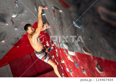 Panoramic man bouldering at an indoor climbing centre. Panoramic man bouldering at an indoor climbing centre. 114467484