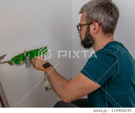 a man mounts wall sockets on plaster a man mounts wall sockets on plaster 114468245