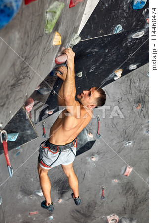 Male professional climber at indoor workout at bouldering centre. 114468474
