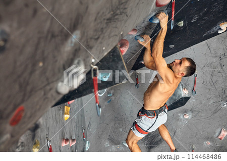 Panoramic man bouldering at an indoor climbing centre. Panoramic man bouldering at an indoor climbing centre. 114468486