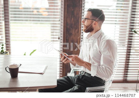 Serious applicant sitting in boardroom, preparing for interview with employer. Serious applicant sitting in boardroom, preparing for interview with employer. 114468707