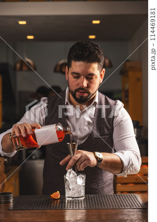 Professional bartender crafting cocktail at bar 114469181