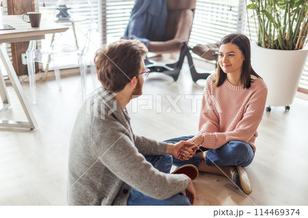 Couple in kitchen spending time together with cup of coffee and smartphone Couple in kitchen spending time together with cup of coffee and smartphone 114469374