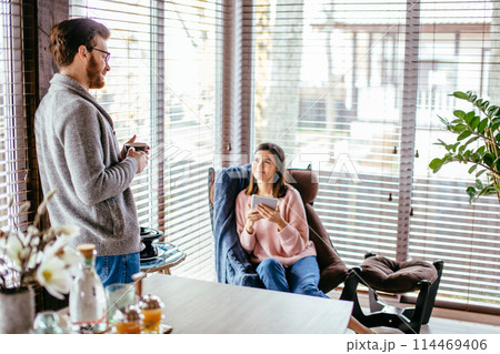 Young couple spending morning in new home, discussing their plans for future. Young couple spending morning in new home, discussing their plans for future. 114469406