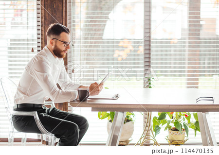Serious applicant sitting in boardroom, preparing for interview with employer. Serious applicant sitting in boardroom, preparing for interview with employer. 114470135