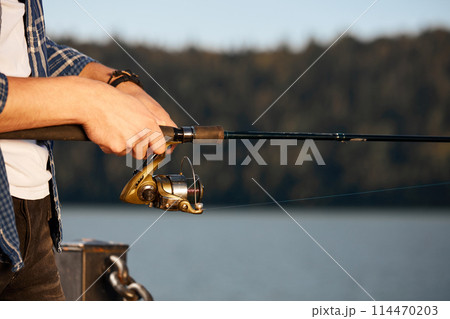 Fisherman standing on riverside and trying to catch fish Fisherman standing on riverside and trying to catch fish 114470203