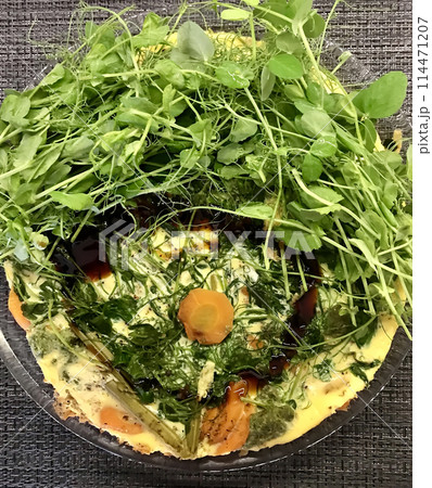 Top view of omelet with green onion, green peas, carrots, sprouted mung beans in a transparent plate at black table. Concept of diet, veganism, healthy foods. Close-up 114471207