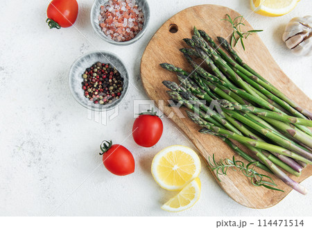 Fresh Asparagus on a Wooden Cutting Board With Seasonal Ingredients Fresh Asparagus on a Wooden Cutting Board With Seasonal Ingredients 114471514