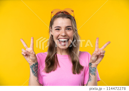 Happy emotions concept. Positive and beautiful young woman laughs poisitively looks aside with carefree face expression wears casual orange sweater isolated over yellow studio background. 114472278