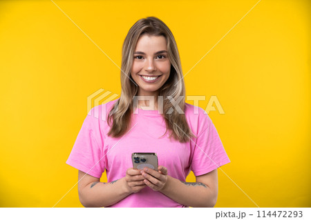 Happy emotions concept. Positive and beautiful young woman laughs poisitively looks aside with carefree face expression wears casual orange sweater isolated over yellow studio background. 114472293