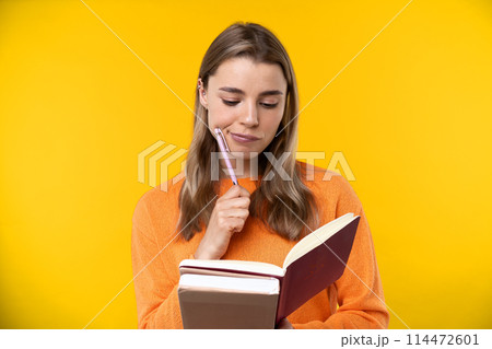Happy emotions concept. Positive and beautiful young woman laughs poisitively looks aside with carefree face expression wears casual orange sweater isolated over yellow studio background. 114472601