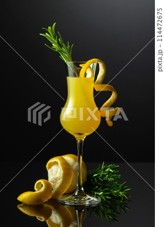 Traditional Italian liqueur Limoncello with rosemary twig on a black background. Traditional Italian liqueur Limoncello with rosemary twig on a black background. 114472675