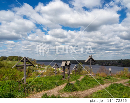 Ancient wooden crosses over the river under white clouds in a blue sky. Ancient wooden crosses over the river under white clouds in a blue sky. 114472836