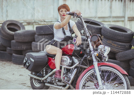 Beautiful girl mechanic on a motorcycle in a roadside workshop Beautiful girl mechanic on a motorcycle in a roadside workshop 114472888