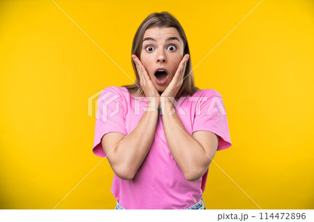 Happy emotions concept. Positive and beautiful young woman laughs poisitively looks aside with carefree face expression wears casual orange sweater isolated over yellow studio background. Happy emotions concept. Positive and beautiful young woman laughs poisitively looks aside with carefree face expression wears casual orange sweater isolated over yellow studio background. 114472896