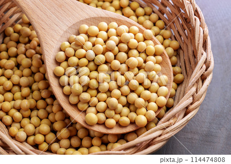 Yellow soybeans in kitchen rattan dish with wooden spoon. Uncooked dried soy grains. Soya beans. Agriculture bio product 114474808