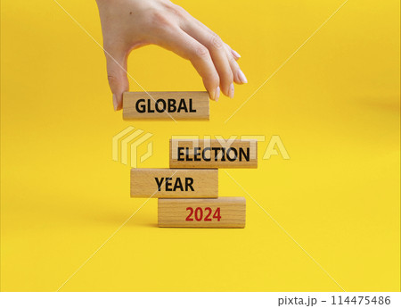Global Election year 2024 symbol. Concept words Global Election year 2024 on wooden blocks. Beautiful yellow background. Businessman hand. Business and Global Election year 2024 concept. Copy space 114475486
