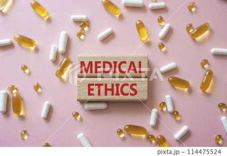 Medical Ethics symbol. Concept word Medical Ethics on wooden blocks. Beautiful pink background with pills. Medicine and Medical Ethics concept. Copy space Medical Ethics symbol. Concept word Medical Ethics on wooden blocks. Beautiful pink background with pills. Medicine and Medical Ethics concept. Copy space 114475524