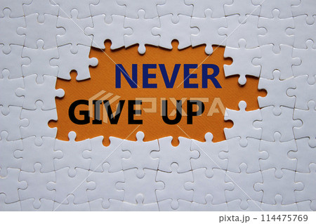 Never give up symbol. Concept words Never give up on white puzzle. Beautiful orange background. Business and Never give up concept. Copy space. 114475769
