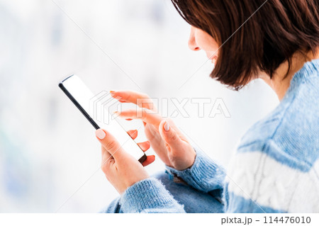 Woman using smartphone in light room Woman using smartphone in light room 114476010