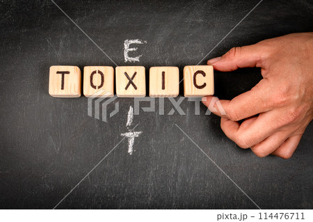 TOXIC and EXIT. Wooden block crossword puzzle and pieces of chalk on a chalkboard background TOXIC and EXIT. Wooden block crossword puzzle and pieces of chalk on a chalkboard background 114476711