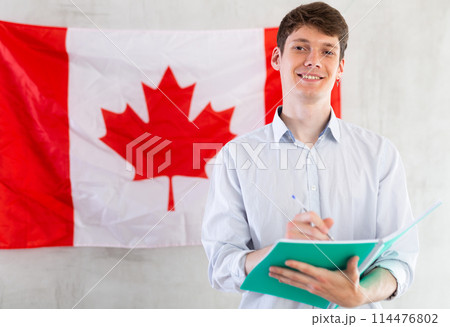 Young guy makes notes against background of Canada flag 114476802