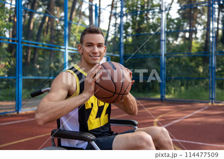 Handsome man with disability playing basketball in wheelchair 114477509