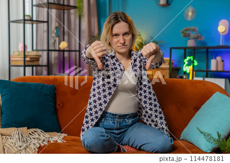 Woman showing thumbs down sign gesture expressing discontent disapproval dissatisfied feedback 114478181