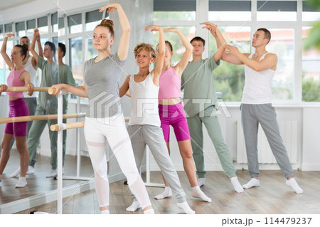 Teacher conducts class with teen girls and boys in ballet studio, observes doing Batman exercise. Teacher conducts class with teen girls and boys in ballet studio, observes doing Batman exercise. 114479237