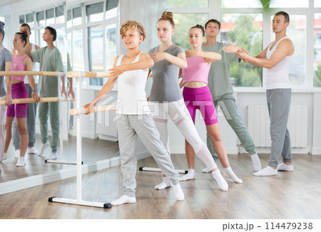 Teenage boys and girls practicing battement tendu position of ballet in dancehall Teenage boys and girls practicing battement tendu position of ballet in dancehall 114479238
