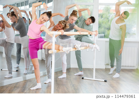 Teen ballet students prepare for classes, near ballet bare stretch legs under man teacher guidance 114479361