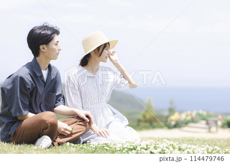 芝生の上でくつろぐ若い男女 114479746