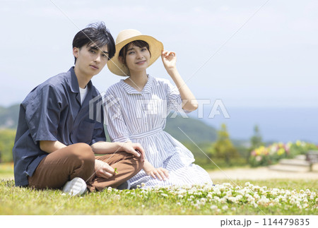芝生の上でくつろぐ若い男女 芝生の上でくつろぐ若い男女 114479835
