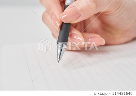 ペンを持ってノートに書く女性の手元 114481640