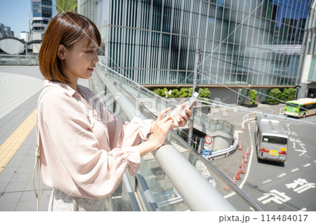 オフィス街でスマホを操作するビジネスウーマン 114484017
