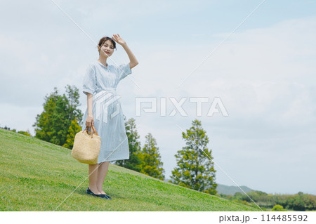 芝生の丘に立つかわいい女性 114485592
