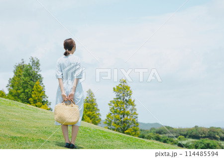 芝生の丘に立つかわいい女性 芝生の丘に立つかわいい女性 114485594