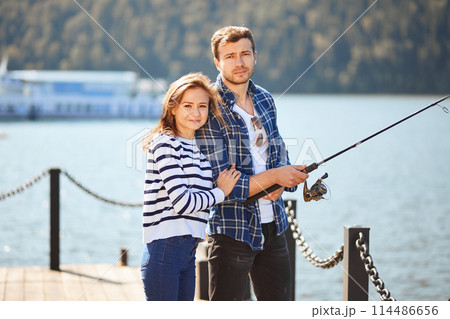 peaceful young couple fishing with pond in autumn in lake 114486656
