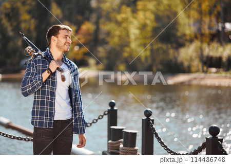 young fisherman with rod and sunglasses fishing in lake 114486748