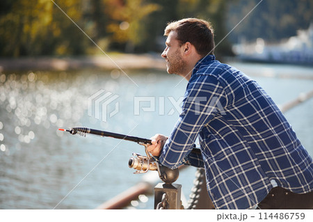 young fisherman with rod and sunglasses fishing in lake 114486759