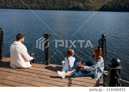 happy family with daughter fishing in pond in fall happy family with daughter fishing in pond in fall 114486831
