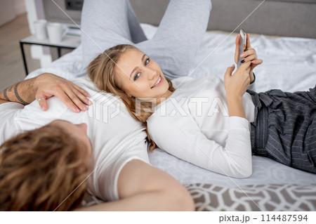 awesome blond girl with smart phone looking at the camera awesome blond girl with smart phone looking at the camera 114487594